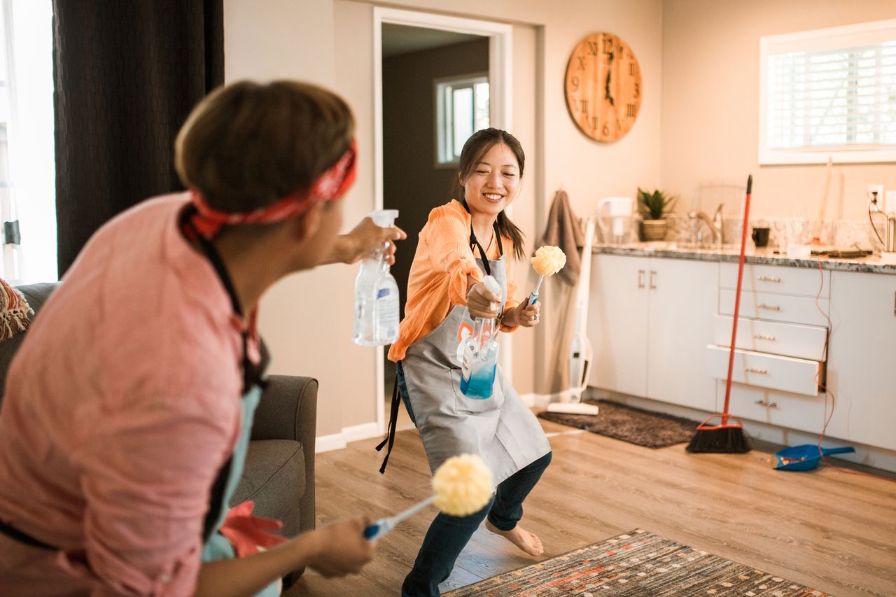 Asian couple enjoying themselves while tidying their home, creating a bright and cheerful atmosphere.